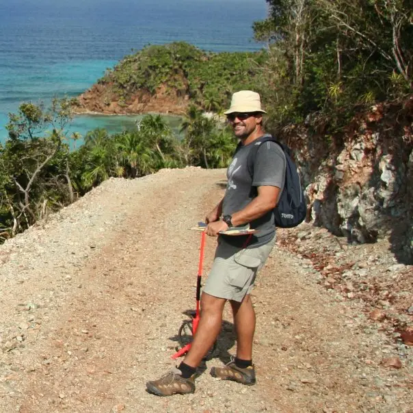 M J Harper with survey equipment on a dirt road on Barbarat island in the Bay Islands
