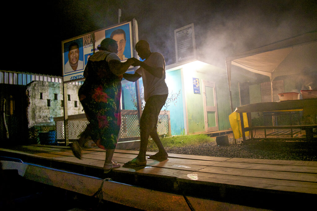 A St. Helene couple dance political candidates for the National Party look on from their campaign posters ( photo credit Tom Leopold )
